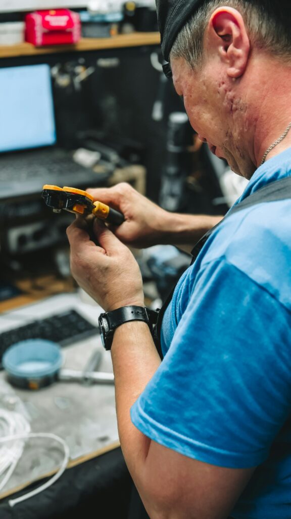 Technician working with tools in an electronics repair workshop, focusing on the task.